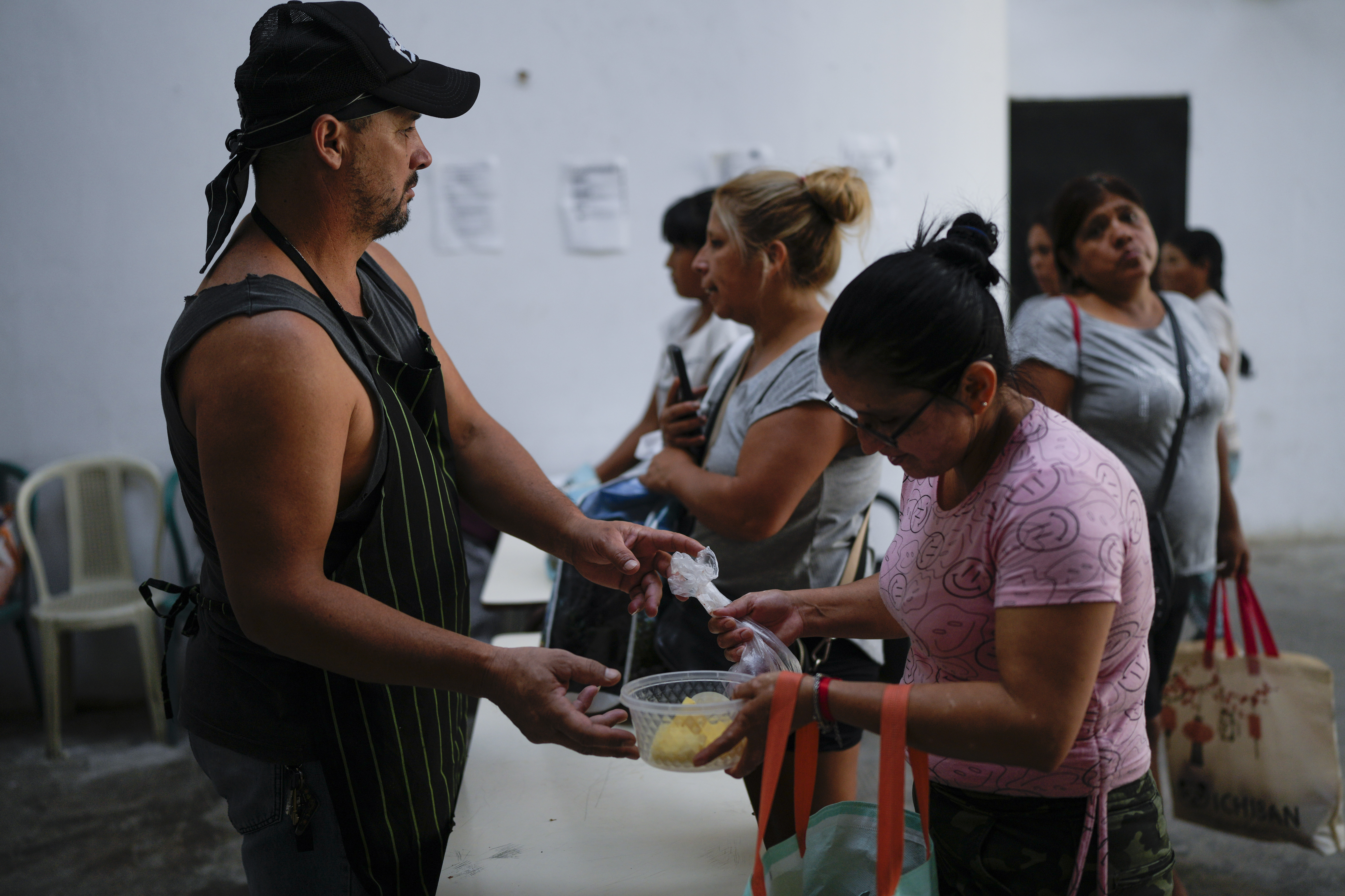 Una vecina recoge comida para llevar a su familia en un comedor comunitario en Buenos Aires, Argentina, el martes 28 de marzo de 2023. Según el Instituto Nacional de Estadísticas y Censos, la pobreza aumentó al 39,2%, en el segundo semestre de 2022, comparada con el 36,5% del semestre anterior. (AP Foto/Natacha Pisarenko)